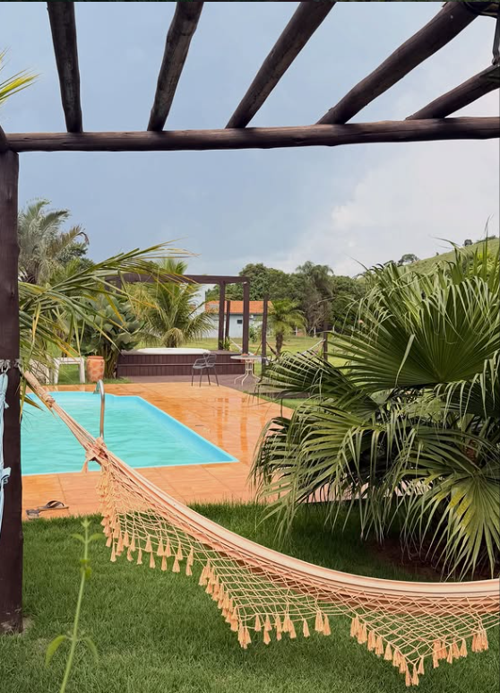 Rede sob o pergolado, com vista para a piscina e o jardim